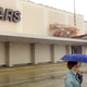 A shopper walks under her umbrella outside a Sears store October 24, 2001 in Niles, IL. Sears, Roebuck and Co. said Wednesday, October 24, 2001 that it is eliminating 4,900 salaried jobs over the next 18 months and revising its merchandise offerings as part of a cost-cutting overhaul. (Photo via Getty Images.)